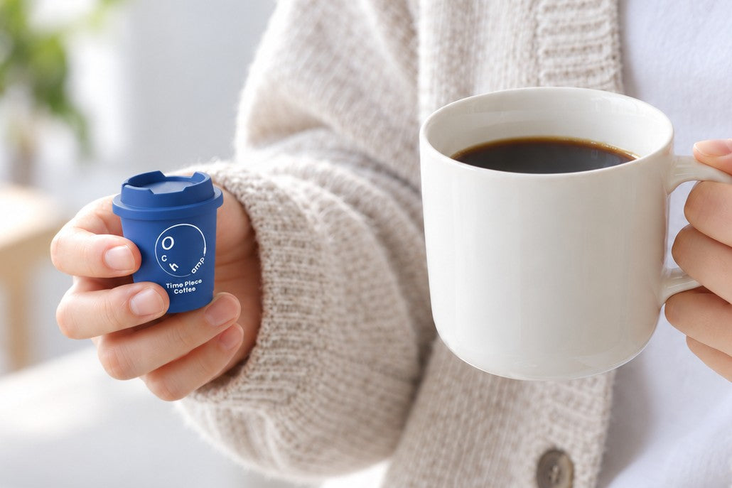 青い小さなカップと、コーヒーの入ったマグを手に持つ